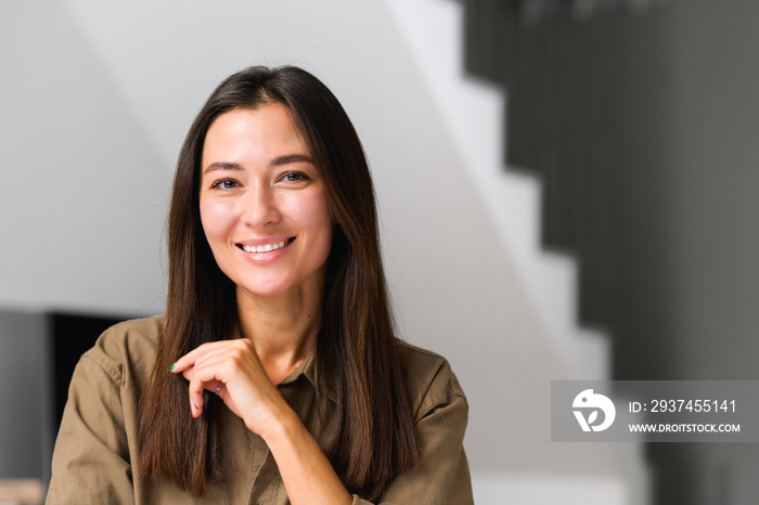 Portrait of charming elegant asian woman with hand under chin smiling at the camera, sitting in the 