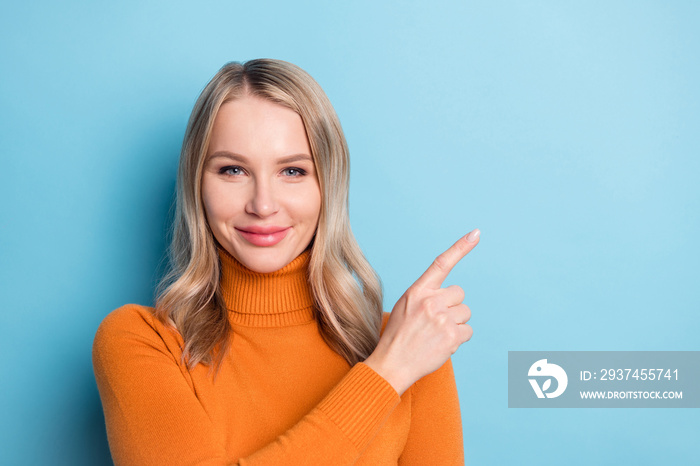 快乐的年轻积极女性的照片，用手指指着空位，在蓝色ba上挑选隔离的offer