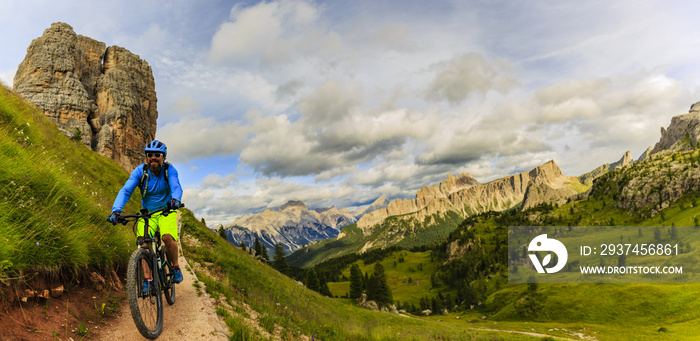 View of cyclist riding mountain bike on single trail in Dolomites, Cinque Torri, South Tirol, Italy