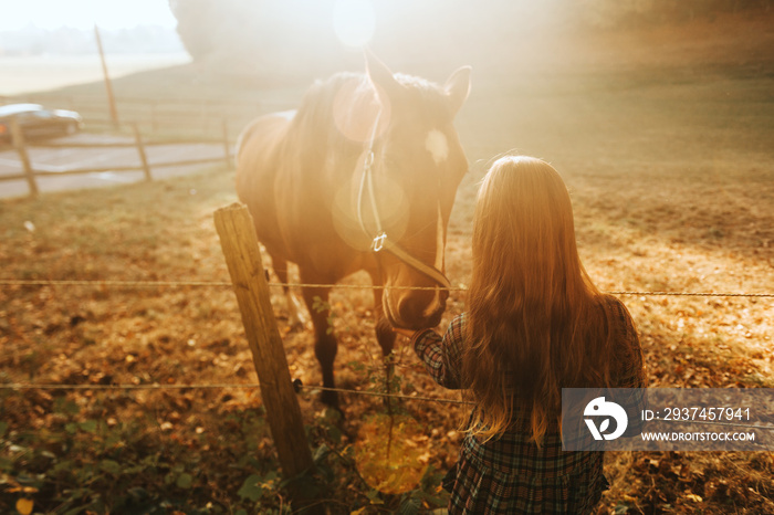 Young kid girl playing with horses in sunset light