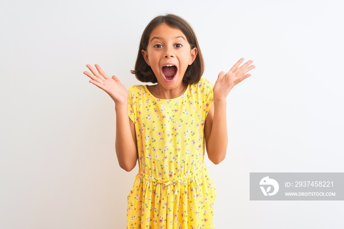 Young beautiful child girl wearing yellow floral dress standing over isolated white background celeb