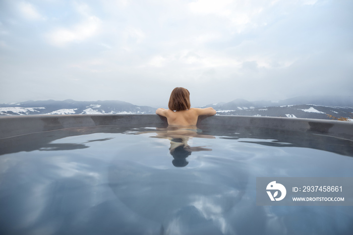 年轻女子冬天在山上的热水浴缸里洗澡。在热水浴缸里休息和恢复的概念