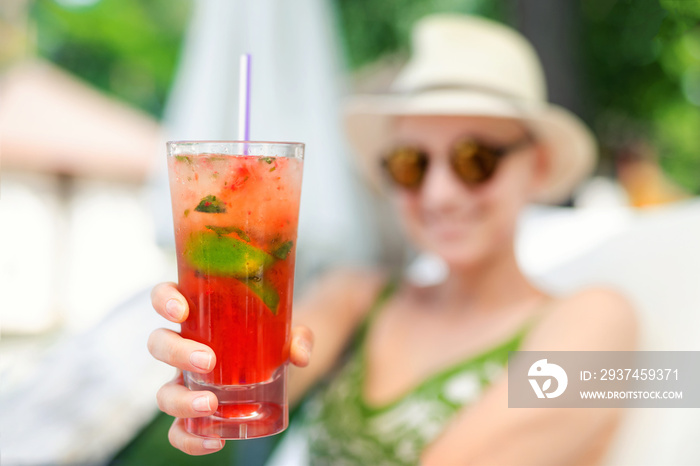 Young beautiful happy woman holding in hand and give glass with fresh cold strawberry non-alcoholic 