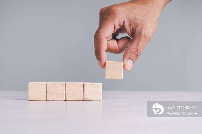 Businessman wearing a blue shirt, arranging the empty wooden blocks with his hands. Which is placed 