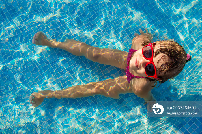 The child is bathing in the pool at the resort. Selective focus.