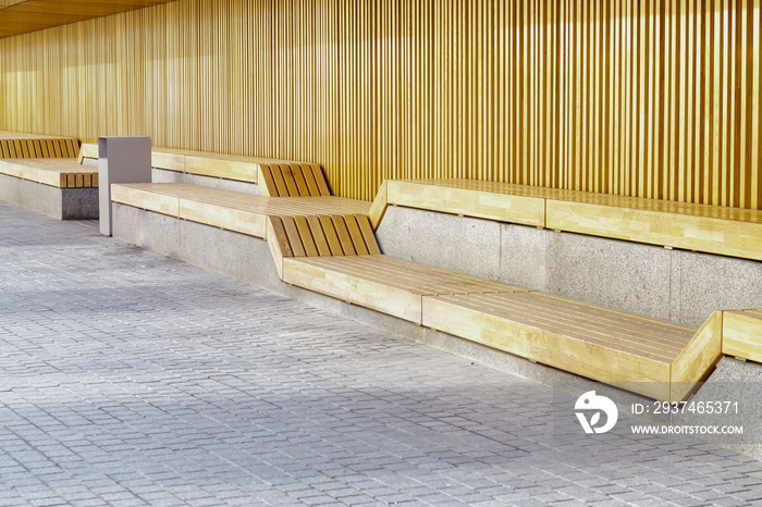 Empty modern wooden benches without people on a sunny day, public places in the city park. City impr