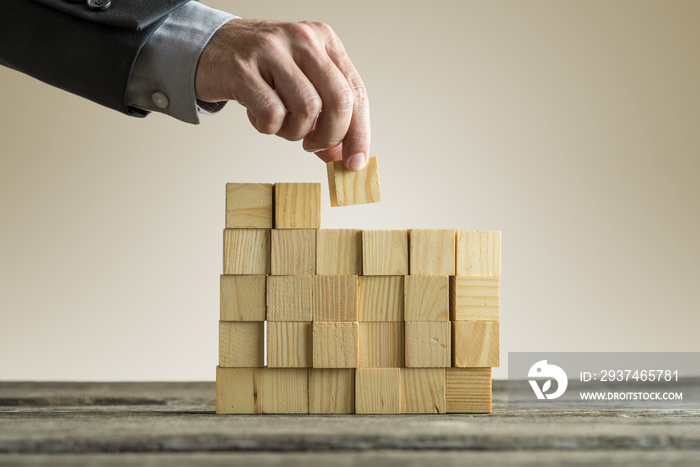 Businessman building a structure with wooden cubes on table surface