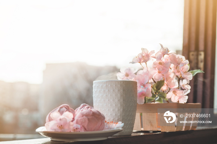 Cozy spring still life: cup of hot tea with spring bouquet of flowers on vintage windowsill with a p