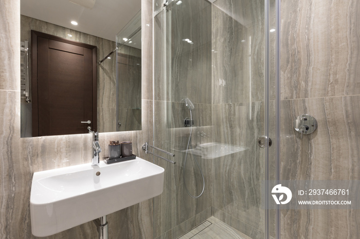 Interior of a luxury bathroom with marble walls and glass shower cabin