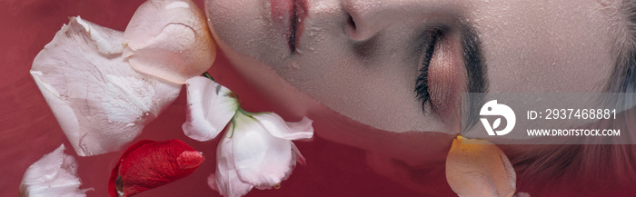 top view of beautiful woman with closed eyes in pink water with rose petals, panoramic shot