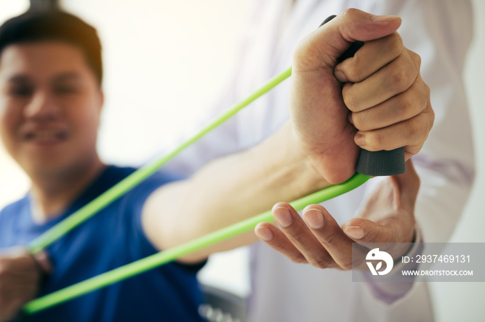 Close up hand patient doing stretching exercise with a flexible exercise band and a physical therapi