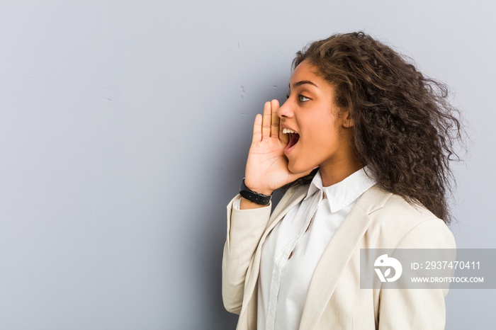 Young african american business woman shouting and holding palm near opened mouth.