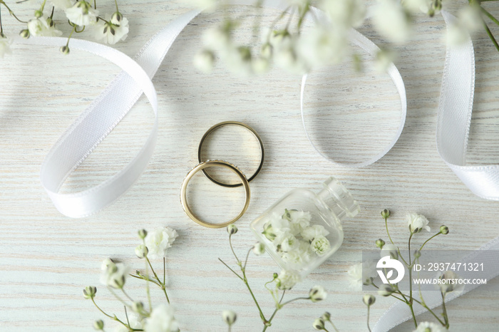 Concept of wedding accessories with wedding rings on white wooden background