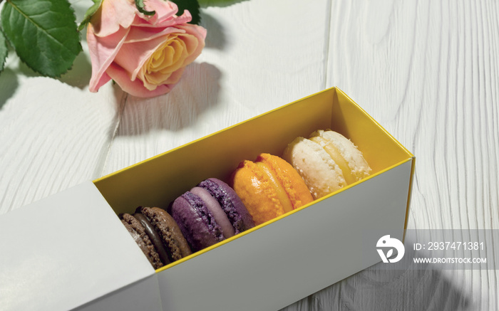 Macarons box and pink rose on wooden table