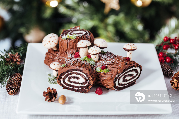 French dessert called Yule log or bûche de Noël with merengue mushrooms and mint leaves on top of ch