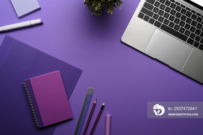 Flat lay computer laptop, potted plant and stationery on purple background.