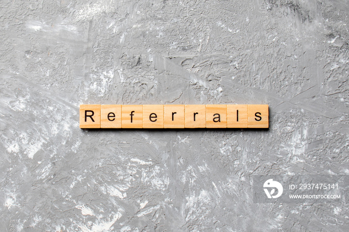 REFERRALS word written on wood block. REFERRALS text on cement table for your desing, concept