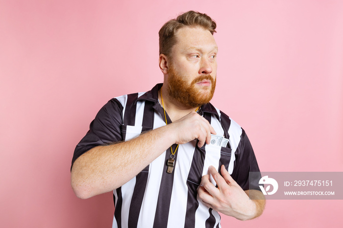 Comic portrait of sport referee wearing field judge uniform isolated on pink studio background. Conc