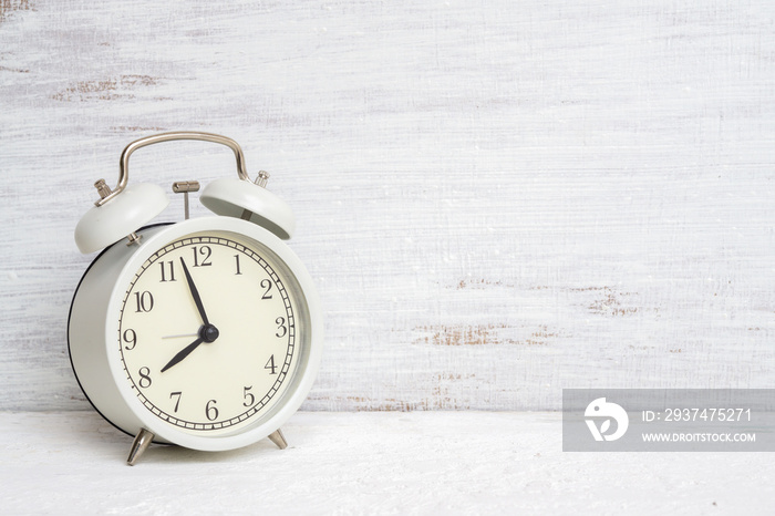 Vintage classic white alarm clock on white grunge background with free space for your advertisement.