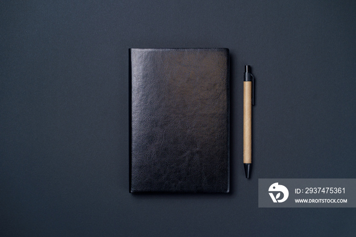 黑色背景纸上的黑色皮革笔记本，笔记本模型，俯视图
