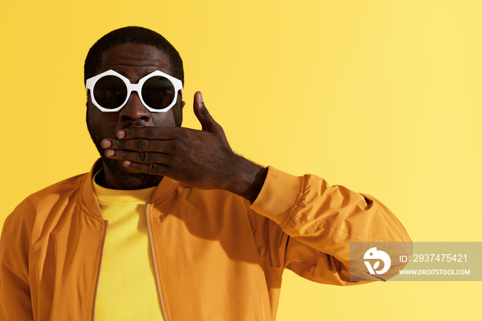 Surprise. Shocked man in fashion sunglasses on yellow background