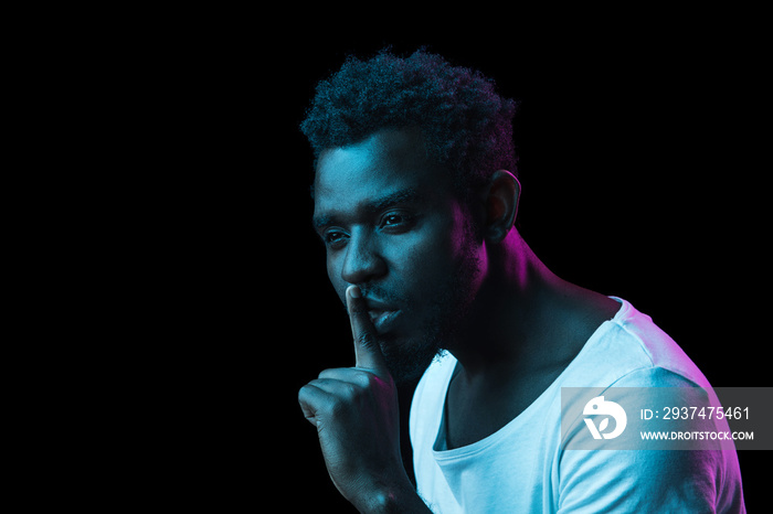 Young African-American man isolated on dark background in neon light