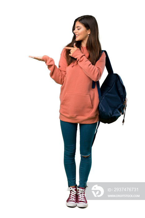 A full-length shot of a Teenager girl with sweatshirt and backpack holding copyspace imaginary on th