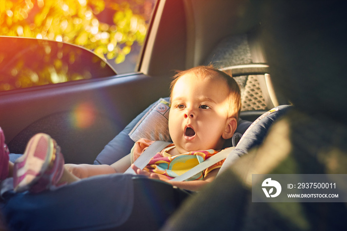 近距离观察坐在现代汽车座椅上的可爱婴儿。新出生的孩子在路上旅行安全。安全的方式
