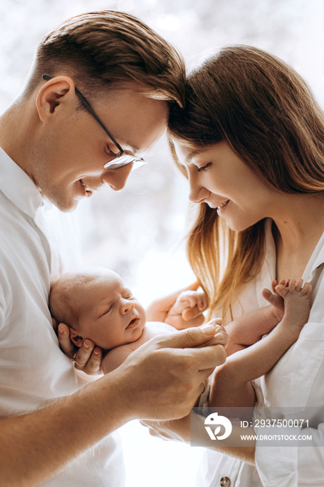 Happy young parents with newborn baby girl, loving mom hold little daughter in arms, caring dad gent