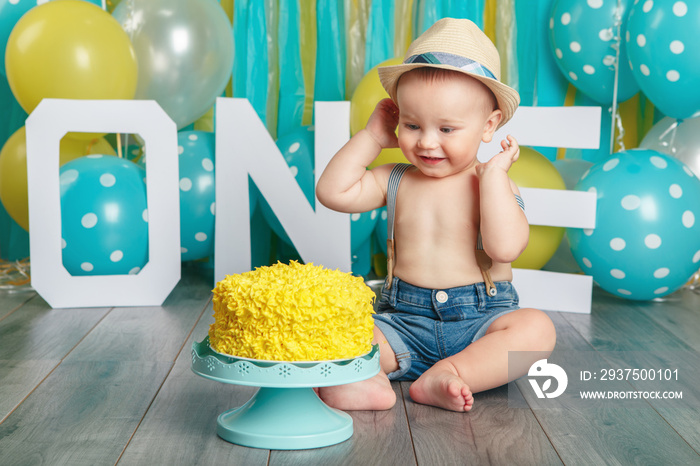 可爱的高加索男婴穿着牛仔裤，戴着帽子庆祝他的第一次出生