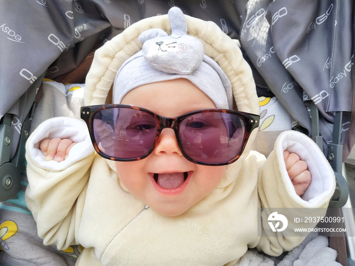 Funny face of baby girl is laughing in sunglasses. Сute baby with sunglasses