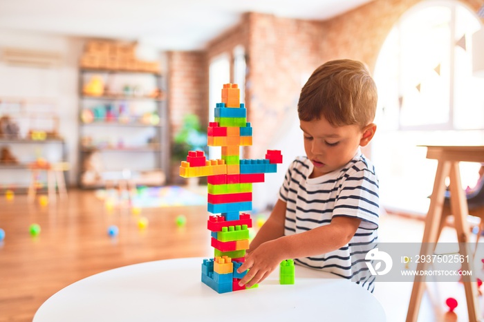 Beautiful toddler boy playing with construction blocks at kindergarten