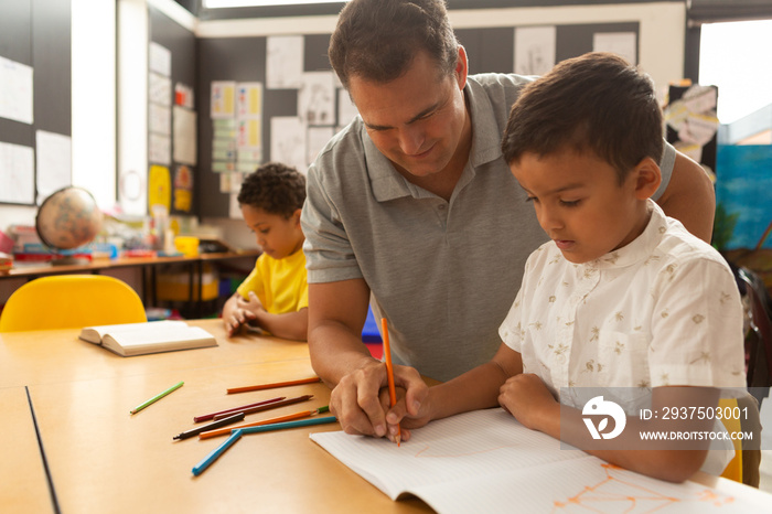 Male teacher teaching a schoolboy in a classroom