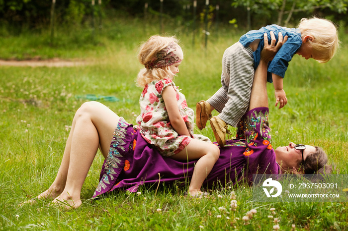 Mother lifting boy while lying on grassy field