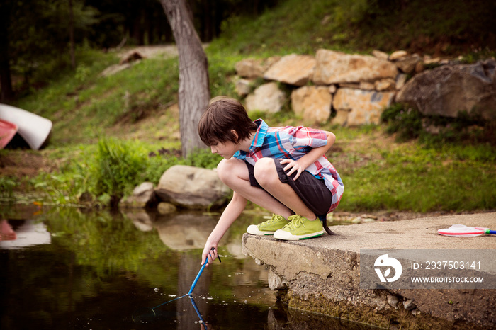 Boy playing with stick on lakeshore