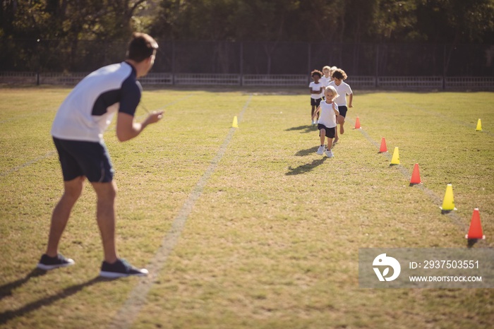 Coach monitoring schoolgirls during running competition