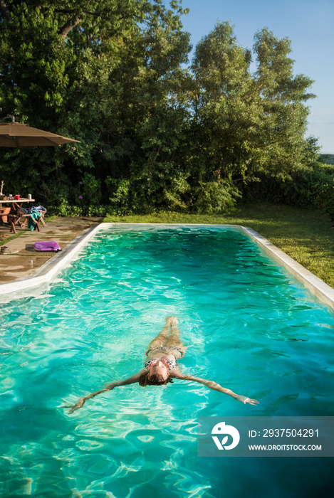 Woman floating on back in swimming pool