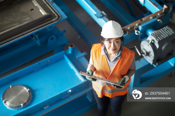 Technician holding equipment part in factory