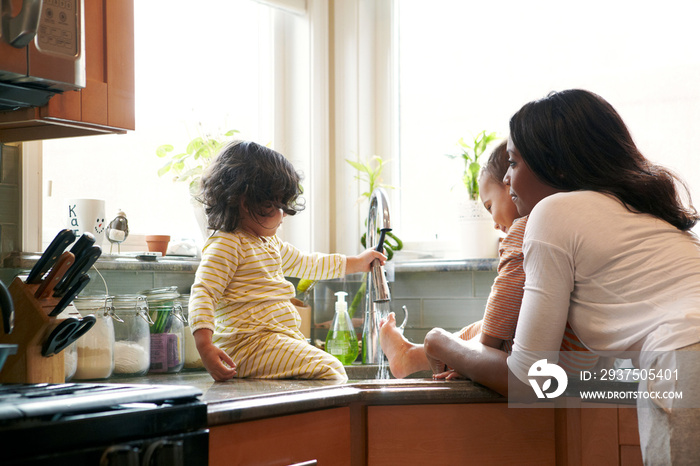 Mother and children (18-23 months) playing in kitchen