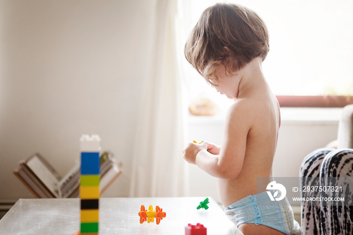 Shirtless girl (2-3) playing with toy block