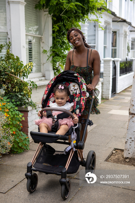 母亲带着婴儿车里的小女儿（12-17个月）散步