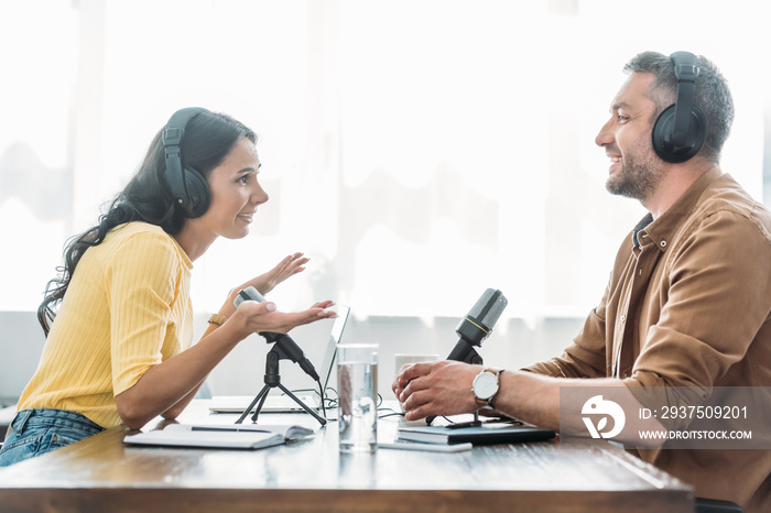 two smiling radio hosts talking while recording podcast in broadcasting studio