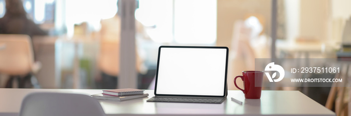 Cropped shot of office desk with blank screen laptop, notebooks and coffee cup in glass partition ro