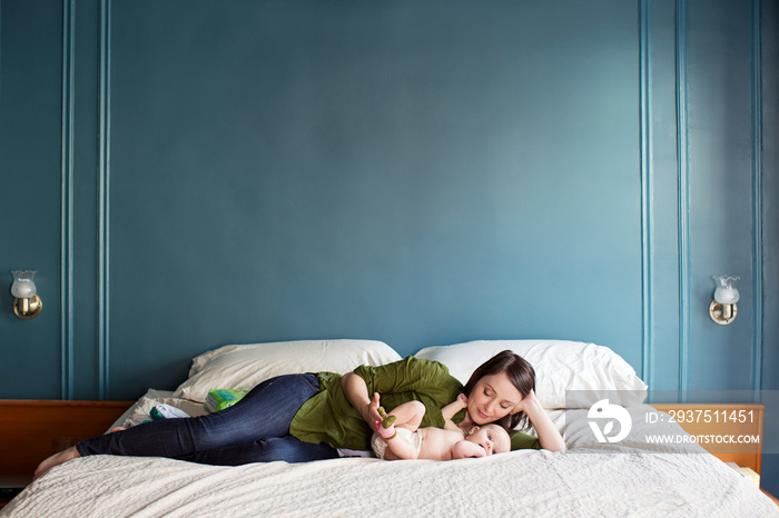 Mother playing with her baby on bed at home