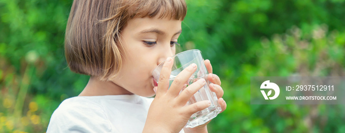 孩子用玻璃杯喝水。选择性聚焦。