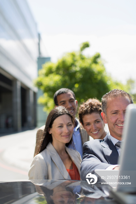 Business people using laptop on car in parking lot