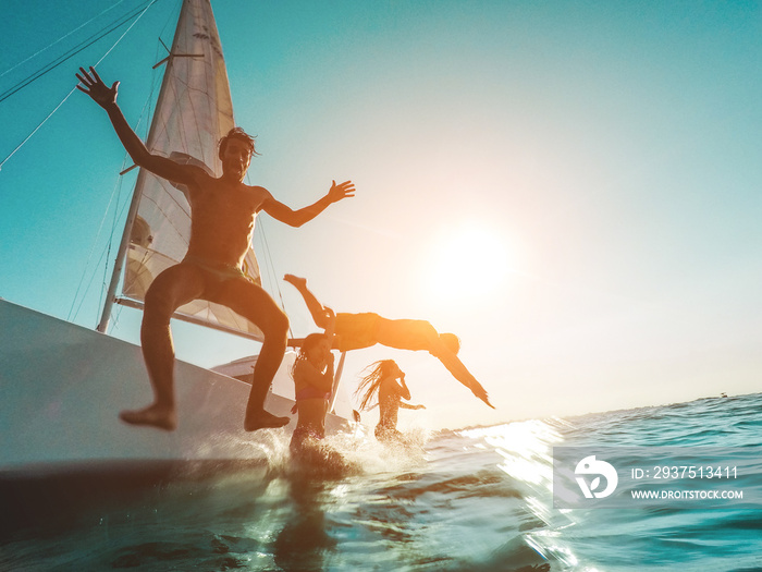 Crazy friends diving from sailing boat into the sea - Young people jumping inside ocean in summer va