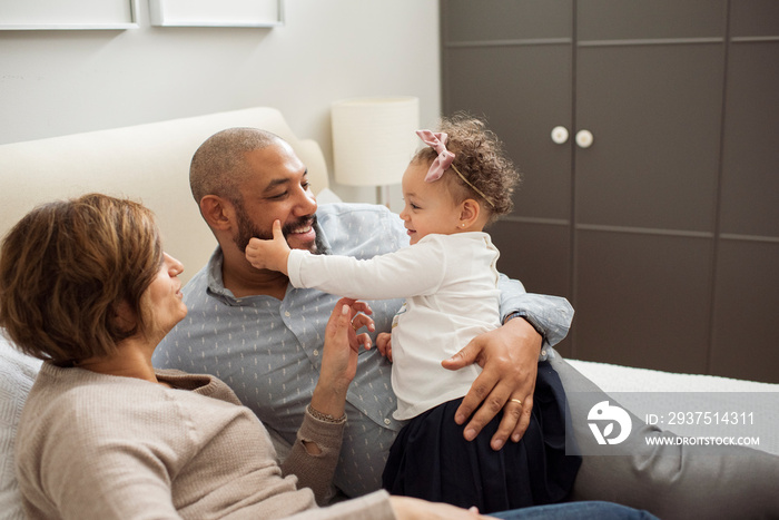 Parents with cute daughter relaxing on bed at home