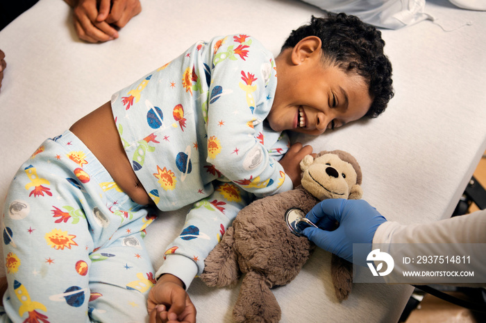 Boy laughing at doctor checking heartbeat of toy