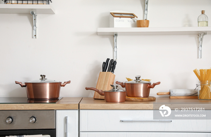 厨房柜台上的铜锅和一套刀具